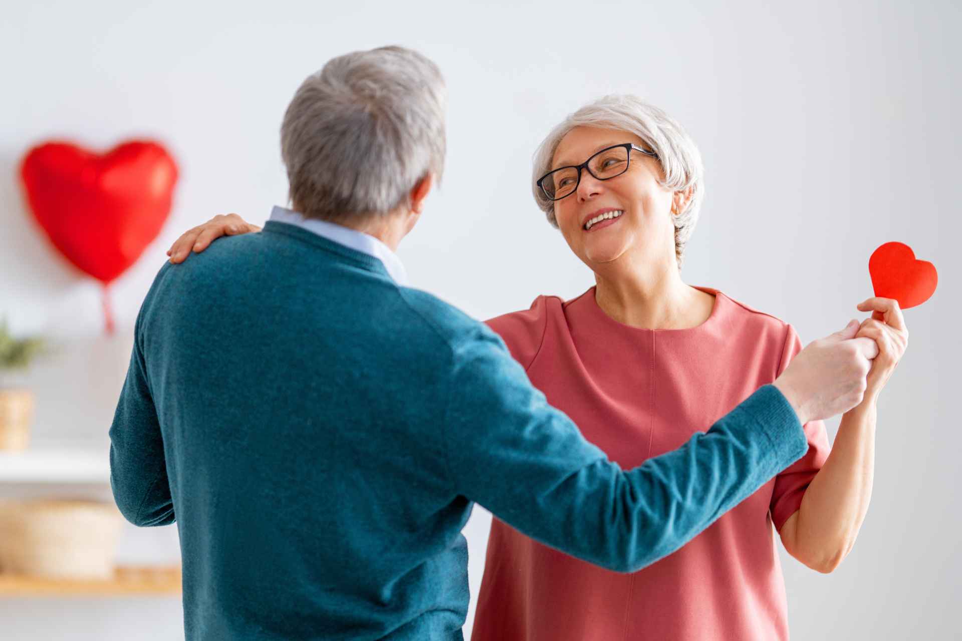 Two seniors dancing, with Valentine's Day decorations in the background