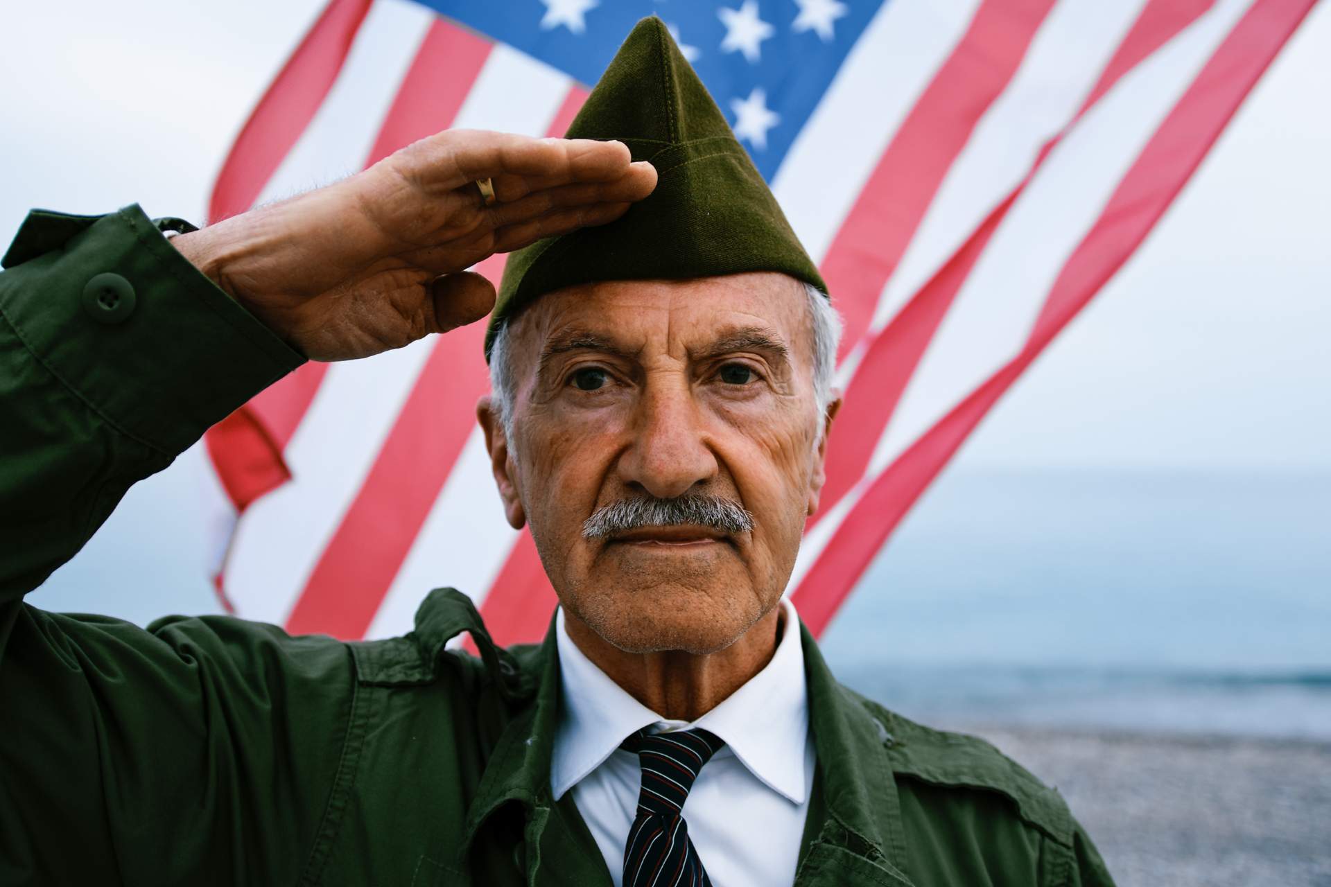 A senior man saluting in front of the American Flag.